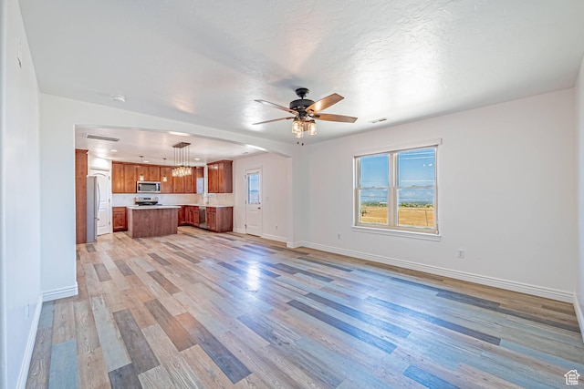 6563 S Days End Ct, West Jordan, UT 84081 - unfurnished living room featuring light wood-type flooring, ceiling fan, and arched walkways