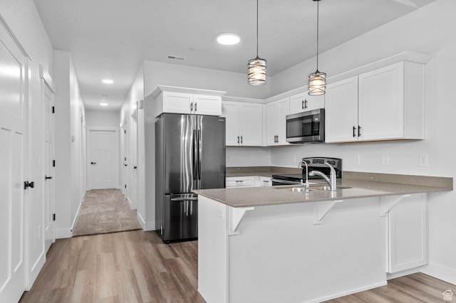 3667 W Canyon Falls Dr Unit S301, Lehi, UT 84043 - kitchen with appliances with stainless steel finishes, a peninsula, light wood finished floors, white cabinets, and decorative light fixtures