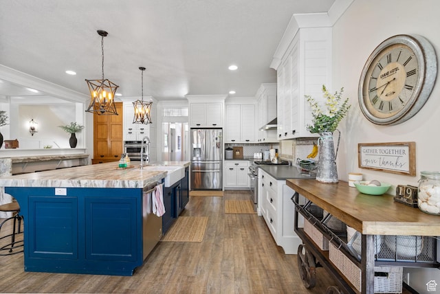 1046 W 1100 N, Pleasant Grove, UT 84062 - kitchen featuring stainless steel appliances, blue cabinetry, white cabinetry, dark wood finished floors, and backsplash