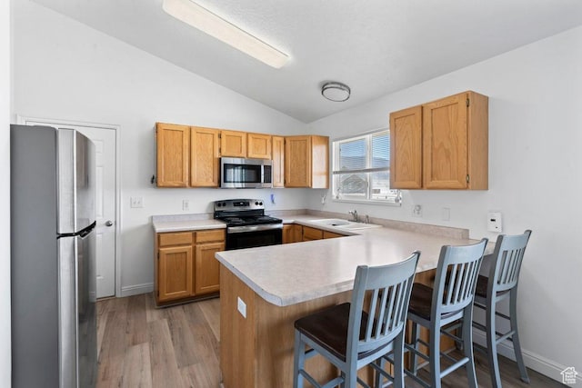 2144 E Easter Dr, Eagle Mountain, UT 84005 - kitchen with appliances with stainless steel finishes, lofted ceiling, a peninsula, light countertops, and light wood-type flooring