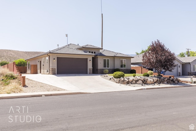 943 N 100 W, Hurricane, UT 84737 - view of front of house with stone siding, a garage, driveway, stucco siding, and a tile roof