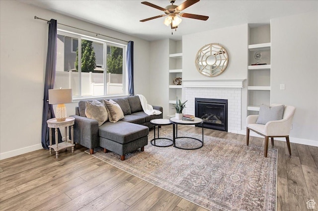 12232 S Sigmon Ln, Herriman, UT 84096 - living room featuring wood finished floors, a ceiling fan, a brick fireplace, and built in shelves