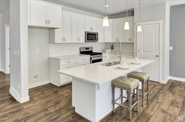 12232 S Sigmon Ln, Herriman, UT 84096 - kitchen with appliances with stainless steel finishes, a kitchen island with sink, dark wood-type flooring, and tasteful backsplash