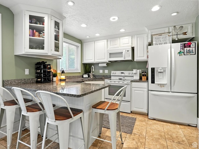 2802 W 4875 S, Roy, UT 84067 - kitchen featuring white appliances, white cabinetry, a peninsula, glass insert cabinets, and a breakfast bar