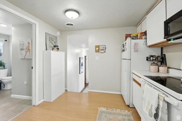 3074 W 3200 N, Benson, UT 84335 - kitchen with black microwave, white electric range, light wood finished floors, light countertops, and white cabinets