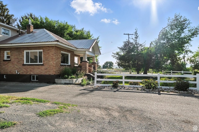 3074 W 3200 N, Benson, UT 84335 - view of home's exterior featuring a chimney, brick siding, and a metal roof