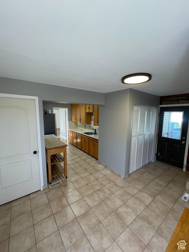 2505 E Elm Ave, Salt Lake City, UT 84109 - kitchen with light countertops, light tile patterned floors, and brown cabinets