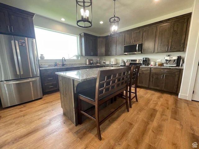 225 W 400 S, Ephraim, UT 84627 - kitchen with appliances with stainless steel finishes, light stone countertops, a breakfast bar area, a kitchen island, and dark brown cabinets