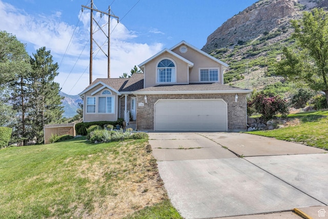 1156 E Avalon Hills Dr N, Ogden, UT 84404 - view of front facade with driveway, an attached garage, a front yard, stucco siding, and a mountain view