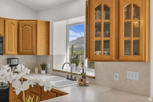1156 E Avalon Hills Dr N, Ogden, UT 84404 - kitchen with glass insert cabinets, light countertops, a mountain view, and brown cabinets