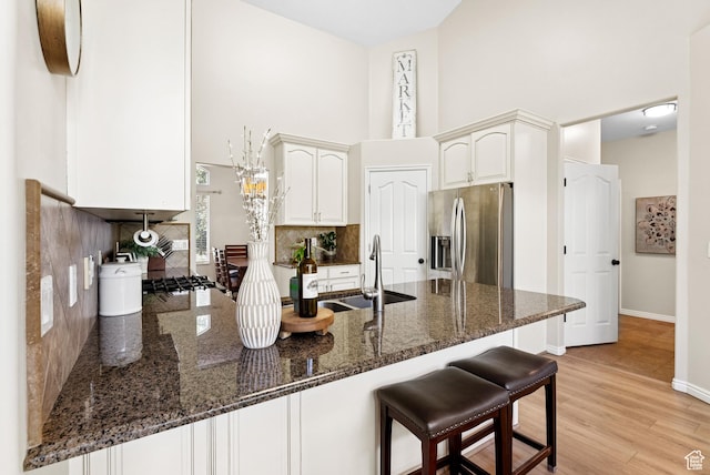 1036 E Fairway Dr, North Salt Lake, UT 84054 - kitchen featuring stainless steel fridge, a peninsula, a high ceiling, decorative backsplash, and dark stone counters