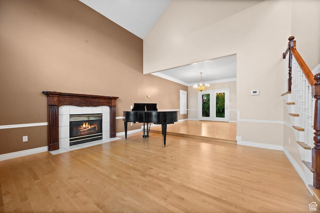 5864 Majestic Pine Dr, Murray, UT 84107 - unfurnished living room with light wood-style flooring, high vaulted ceiling, a tile fireplace, stairs, and french doors