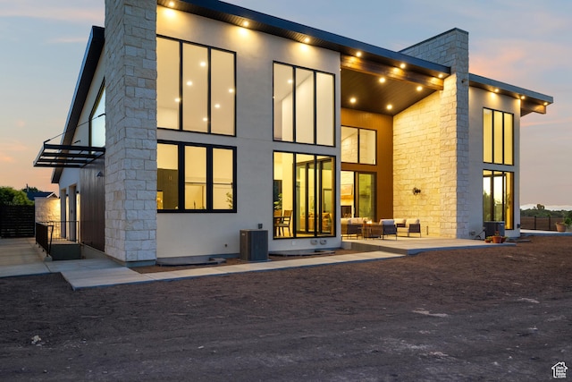1882 N Main St, Mapleton, UT 84664 - back of property at dusk with a balcony, stone siding, outdoor lounge area, and a chimney