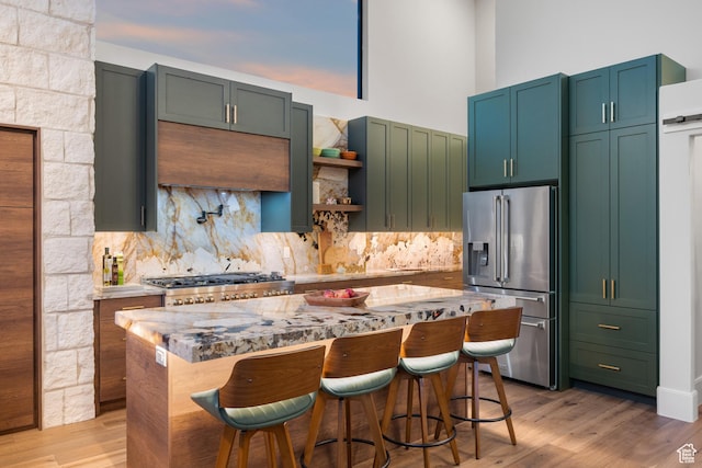 1882 N Main St, Mapleton, UT 84664 - kitchen with stainless steel fridge, tasteful backsplash, a center island, a breakfast bar area, and a towering ceiling