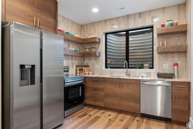 1882 N Main St, Mapleton, UT 84664 - kitchen with appliances with stainless steel finishes, open shelves, backsplash, light wood-style floors, and brown cabinets