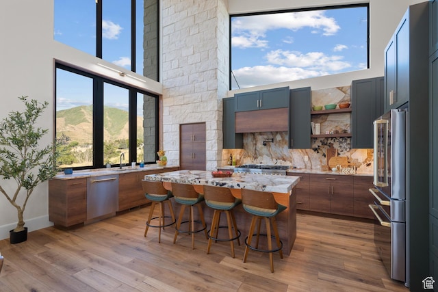 1882 N Main St, Mapleton, UT 84664 - kitchen with stainless steel appliances, light wood-style floors, a center island, light stone countertops, and a high ceiling