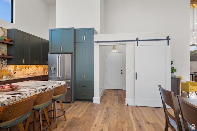 1882 N Main St, Mapleton, UT 84664 - kitchen featuring high end refrigerator, a towering ceiling, a barn door, open shelves, and tasteful backsplash