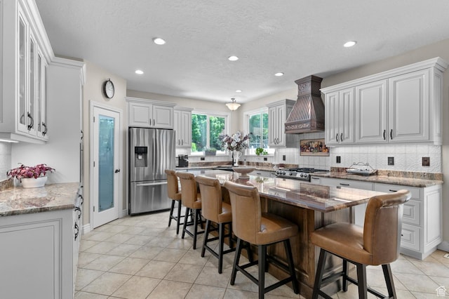 352 E Maple Dr, Alpine, UT 84004 - kitchen with stainless steel fridge with ice dispenser, custom exhaust hood, backsplash, a kitchen bar, and recessed lighting
