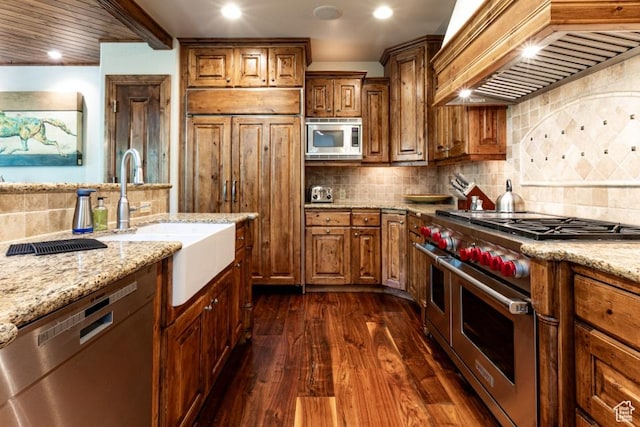 8789 Marsac Ave Unit 4, Park City, UT 84060 - kitchen featuring appliances with stainless steel finishes, premium range hood, dark wood-type flooring, brown cabinets, and tasteful backsplash