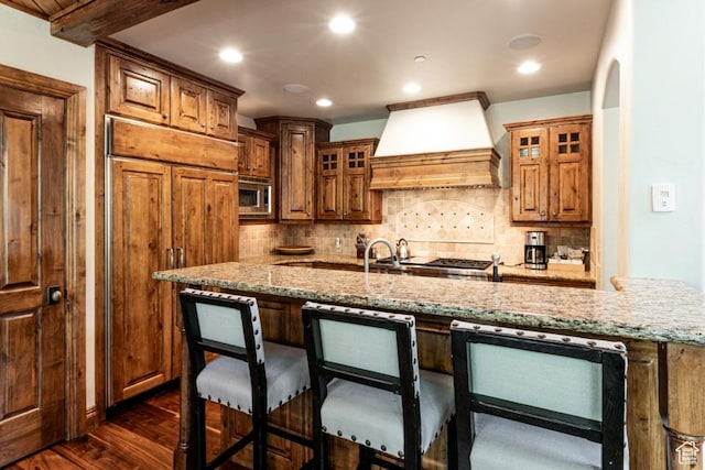 8789 Marsac Ave Unit 4, Park City, UT 84060 - kitchen featuring custom exhaust hood, built in appliances, dark wood-type flooring, a breakfast bar area, and light stone countertops