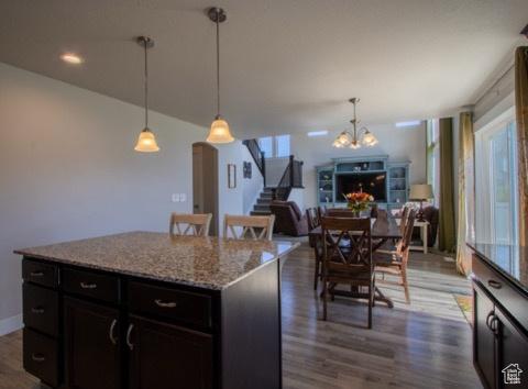 4910 N Deseret Peak Dr, Eagle Mountain, UT 84005 - kitchen featuring a chandelier, dark wood-style floors, open floor plan, a kitchen island, and light stone countertops