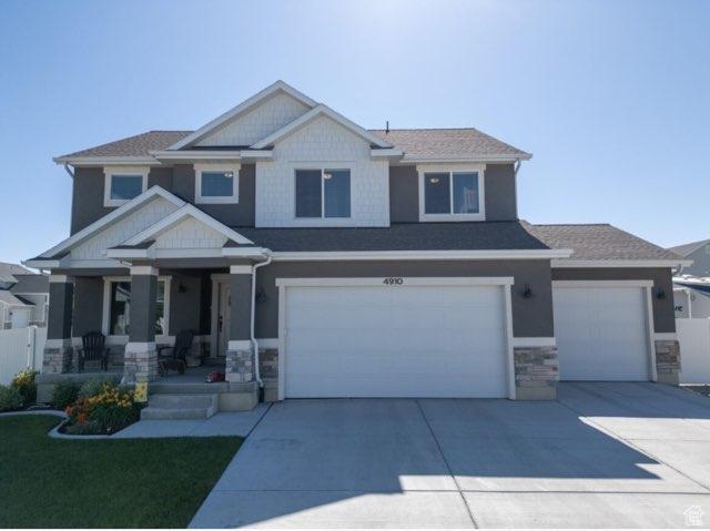 4910 N Deseret Peak Dr, Eagle Mountain, UT 84005 - craftsman-style house with a porch, concrete driveway, an attached garage, and stone siding