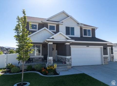 4910 N Deseret Peak Dr, Eagle Mountain, UT 84005 - craftsman-style home featuring an attached garage, concrete driveway, and stone siding