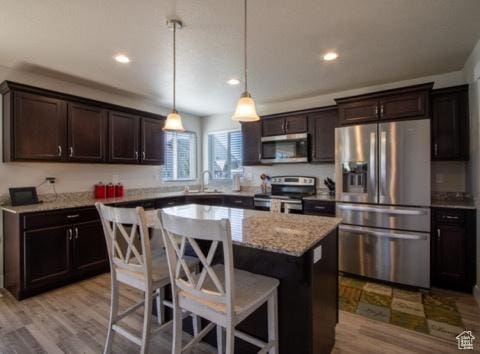 4910 N Deseret Peak Dr, Eagle Mountain, UT 84005 - kitchen with stainless steel appliances, dark brown cabinets, a center island, recessed lighting, and wood finished floors