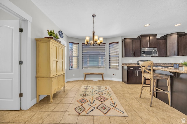 169 W Barry Links Way S, Salt Lake, UT 84115 - kitchen with stainless steel microwave, a chandelier, light tile patterned flooring, dark brown cabinets, and hanging light fixtures