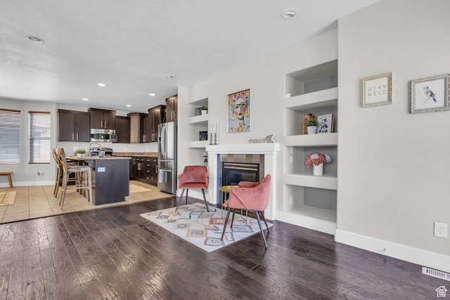 169 W Barry Links Way S, Salt Lake, UT 84115 - living area with built in features, light wood-style floors, a glass covered fireplace, a textured ceiling, and recessed lighting