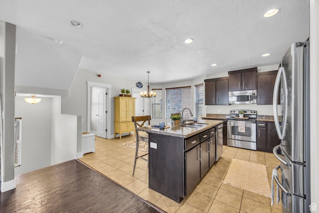 169 W Barry Links Way S, Salt Lake, UT 84115 - kitchen with appliances with stainless steel finishes, a kitchen bar, dark brown cabinetry, a chandelier, and stone countertops