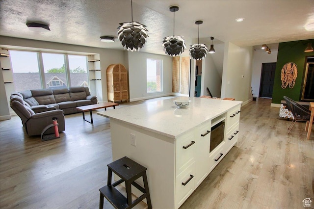 2839 S Oakwood Dr, Bountiful, UT 84010 - kitchen featuring white cabinetry, open floor plan, light wood-style floors, a center island, and light stone counters