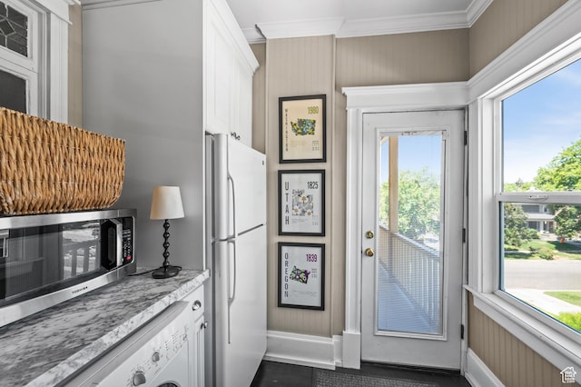 557 E 1 St Ave Unit 12, Salt Lake City, UT 84103 - kitchen featuring freestanding refrigerator, ornamental molding, washer / clothes dryer, plenty of natural light, and white cabinets