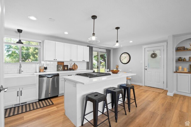 440 E Willow Ave, Murray, UT 84107 - kitchen with appliances with stainless steel finishes, white cabinets, light countertops, tasteful backsplash, and a breakfast bar area