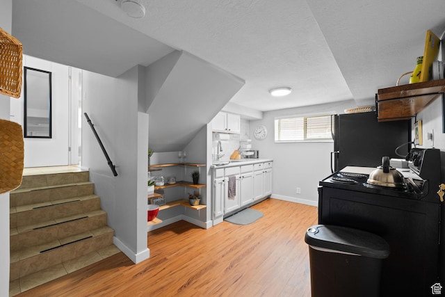 440 E Willow Ave, Murray, UT 84107 - kitchen featuring light wood finished floors, white cabinets, freestanding refrigerator, washer / dryer, and black electric range