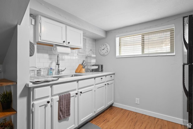 440 E Willow Ave, Murray, UT 84107 - kitchen with backsplash, white cabinets, light wood finished floors, light countertops, and fridge