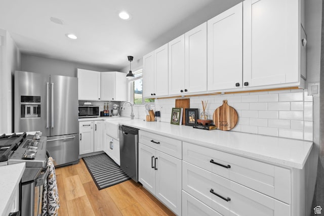 440 E Willow Ave, Murray, UT 84107 - kitchen featuring appliances with stainless steel finishes, light wood-style flooring, white cabinets, backsplash, and recessed lighting