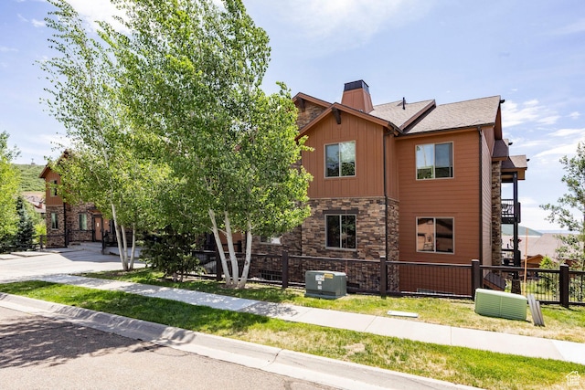 1261 W Black Rock Trl Unit 39D, Kamas, UT 84036 - view of side of home featuring stone siding, a fenced front yard, a chimney, and board and batten siding
