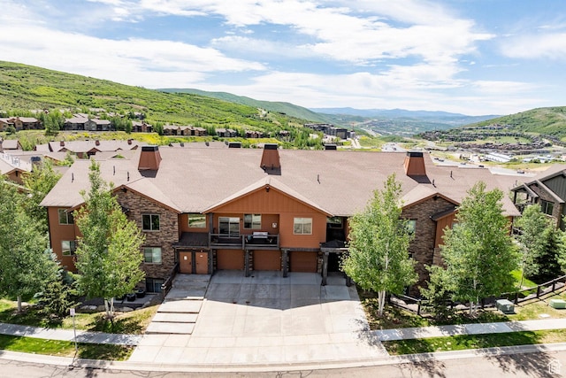 1261 W Black Rock Trl Unit 39D, Kamas, UT 84036 - view of front of home with a garage, stone siding, a mountain view, a chimney, and concrete driveway