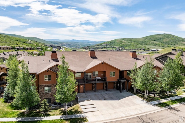 1261 W Black Rock Trl Unit 39D, Kamas, UT 84036 - view of front facade featuring a garage, concrete driveway, a mountain view, stone siding, and a chimney