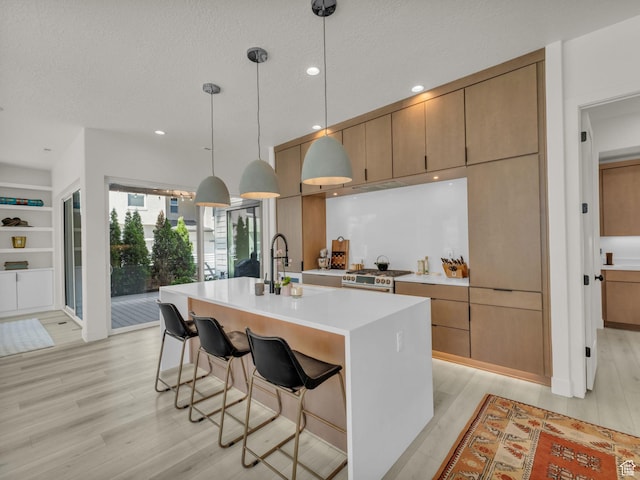 11609 S Dorian Dr W, South Jordan, UT 84009 - kitchen with light wood-style floors, light countertops, a center island with sink, decorative light fixtures, and recessed lighting