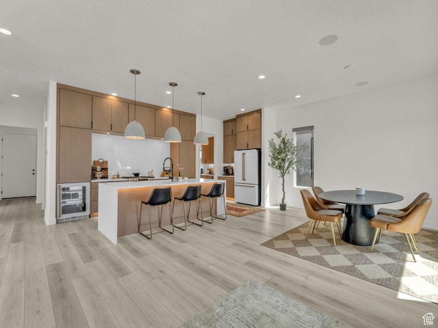 11609 S Dorian Dr W, South Jordan, UT 84009 - kitchen with freestanding refrigerator, beverage cooler, light wood-style floors, a kitchen breakfast bar, and recessed lighting