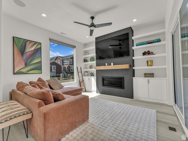 11609 S Dorian Dr W, South Jordan, UT 84009 - living room featuring a glass covered fireplace, a ceiling fan, light wood-style floors, recessed lighting, and built in features