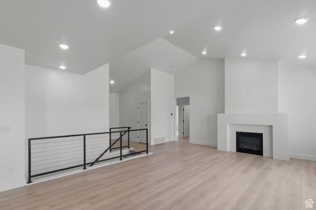 168 N 870 E, Tremonton, UT 84337 - unfurnished living room with wood finished floors, recessed lighting, high vaulted ceiling, and a glass covered fireplace