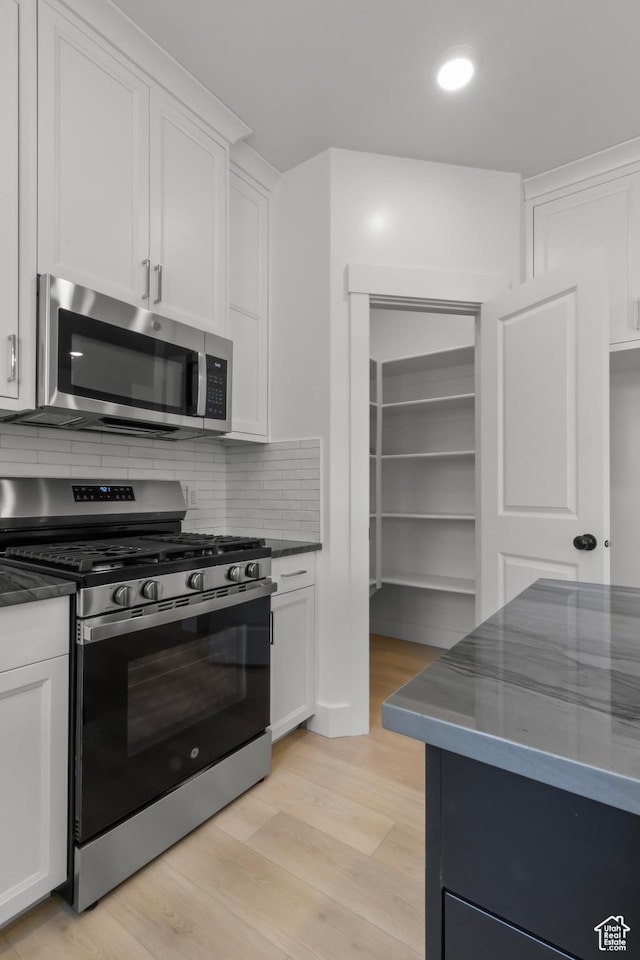 168 N 870 E, Tremonton, UT 84337 - kitchen with appliances with stainless steel finishes, white cabinets, decorative backsplash, light wood-type flooring, and recessed lighting