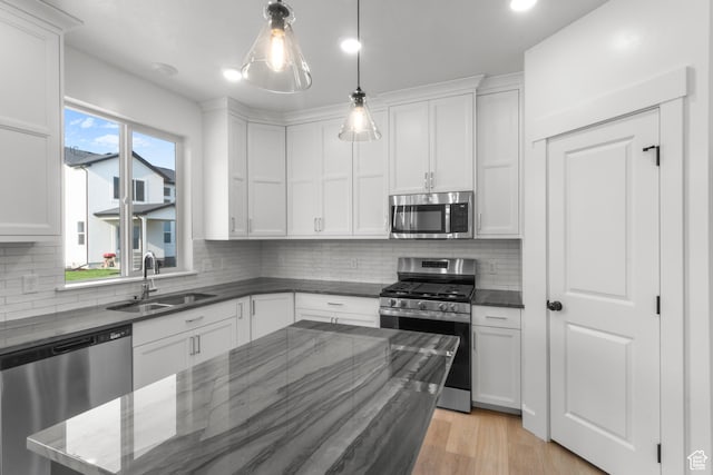 168 N 870 E, Tremonton, UT 84337 - kitchen featuring stainless steel appliances, white cabinets, backsplash, decorative light fixtures, and light wood finished floors