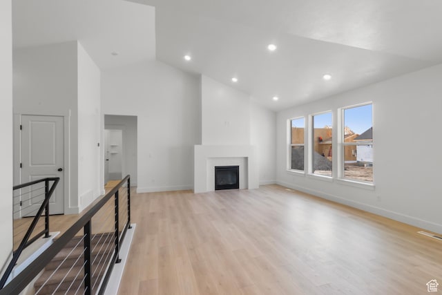168 N 870 E, Tremonton, UT 84337 - unfurnished living room with high vaulted ceiling, a glass covered fireplace, light wood finished floors, and recessed lighting