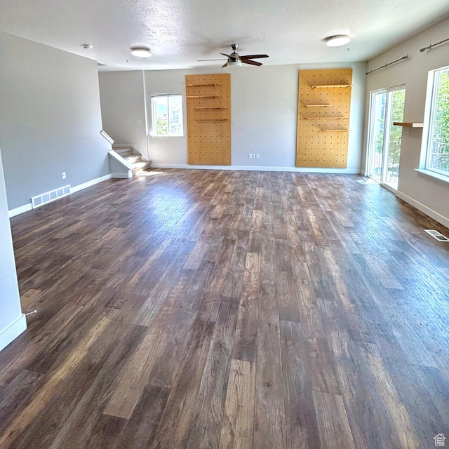 5382 W Tioga Pl, Herriman, UT 84096 - unfurnished living room with dark wood-style flooring, ceiling fan, and stairs