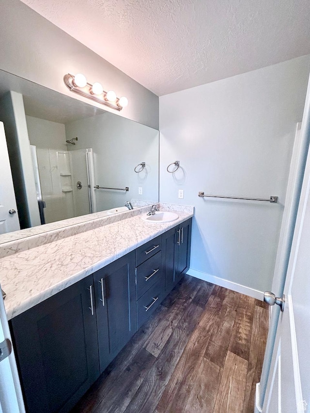 5382 W Tioga Pl, Herriman, UT 84096 - bathroom featuring wood finished floors, double vanity, an enclosed shower, and a textured ceiling