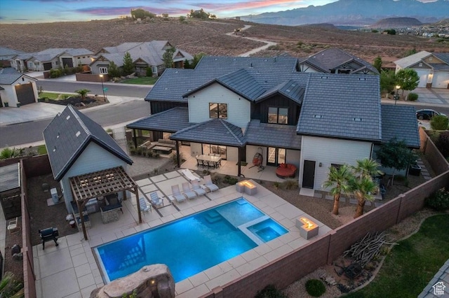 772 E Prairie Way, Washington, UT 84780 - back of property at dusk with a fenced backyard, a pool with connected hot tub, a mountain view, outdoor lounge area, and a residential view